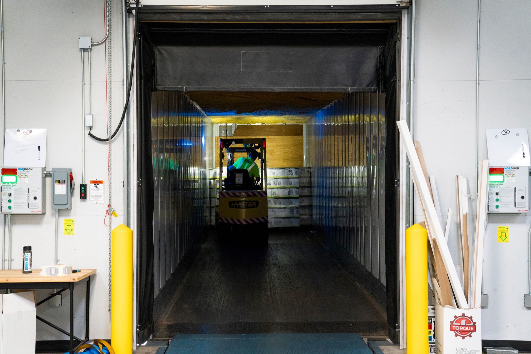 Loading dock — a forklift unloading goods from a trailer at an industrial bay.